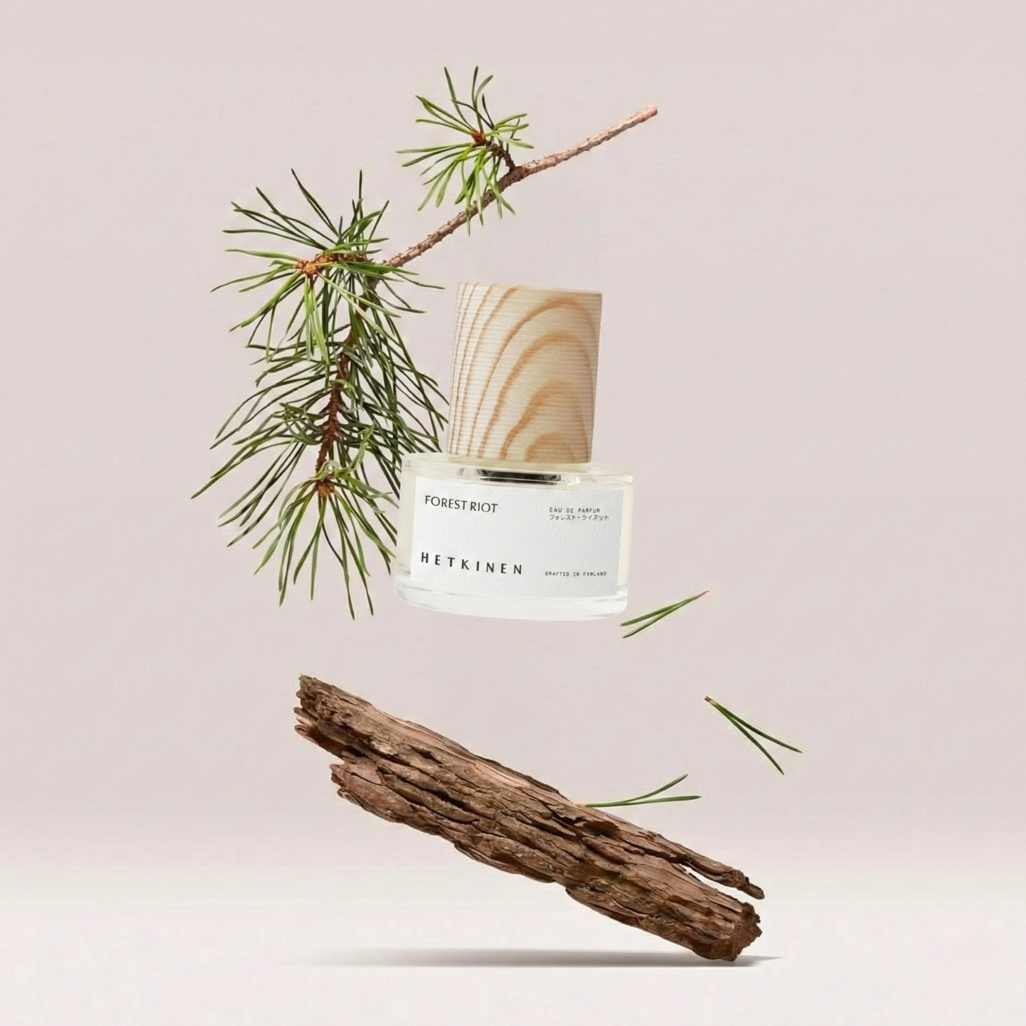 Perfume bottle labeled 'Metkinen' with a pine branch and wooden log on a light background