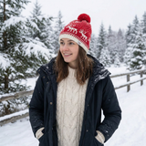 Woman wearing a red and white knit hat with a pom-pom in a snowy forest.