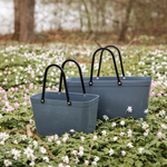 Two blue tote bags with black handles on a field of white flowers.