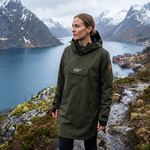 Person wearing a green rain poncho standing in a mountainous landscape with a lake.
